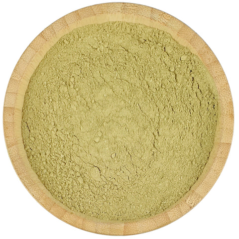Green powder in a wooden bowl on a white background