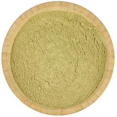 Green powder in a wooden bowl on a white background